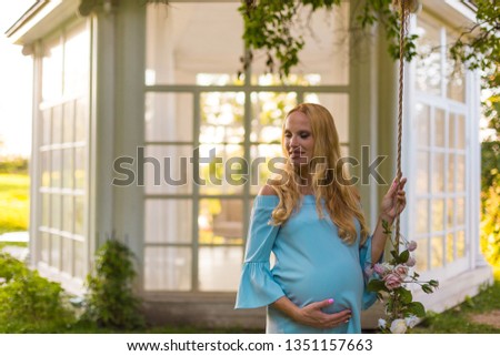 Pregnant blonde woman in park