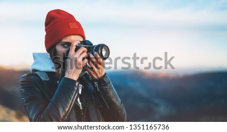 hipster tourist girl hold in hands take photography click on modern photo camera, photographer look on camera technology, journey landscape vacation concept, sun flare mountain