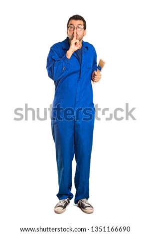 A full-length shot of a Painter man showing a sign of silence gesture putting finger in mouth on isolated white background