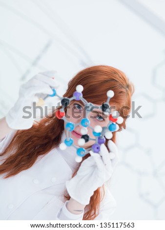 macro of a student in a chemistry lab holding in hands and analyzing DMT molecular model and a white board on the background