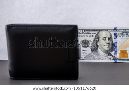 hundred dollar bills and a black wallet