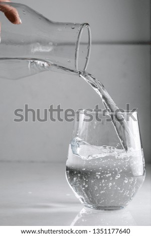 water is poured into a glass from a decanter