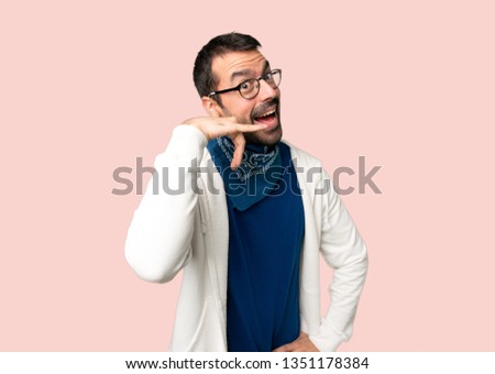 Handsome man with glasses making phone gesture. Call me back sign on isolated pink background