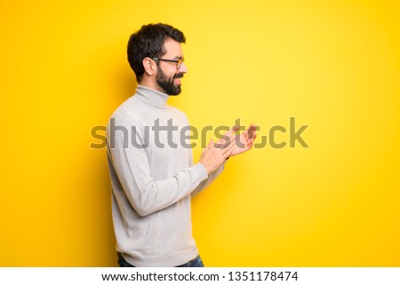 Man with beard and turtleneck applauding after presentation in a conference
