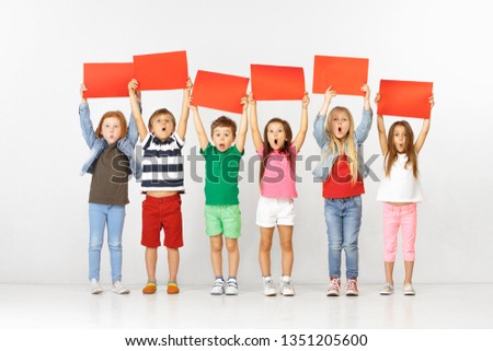 Group of happy surprised children with red empty banners isolated in white studio background. Education and advertising concept