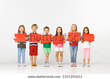 Group of happy smiling children with red empty banners isolated in white studio background. Education and advertising concept