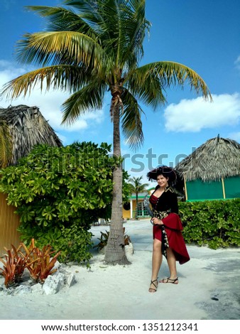 Pirate lady in corsair costume on shoreside with palm loocking for treasure next to beach. Pirate party costume. Cute brave pirate girl on island background. Portrait of woman  pirate theme