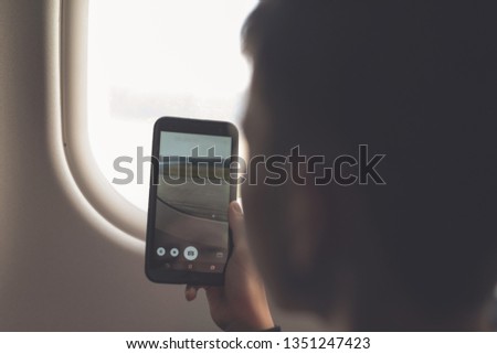 Caucasian boy using smartphone and taking picture during air flight.  Safety travel with kid. concept 