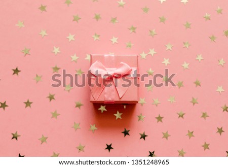 Gift box with holographic golden stars. Living Coral - Color of the Year 2019. Festive backdrop. Top view