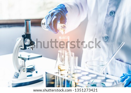  Equipment and science experiments oil pouring scientist with test tube yellow making research in laboratory. Royalty-Free Stock Photo #1351273421