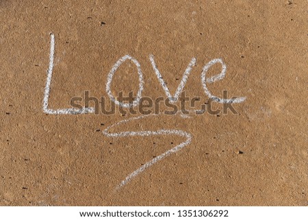 the word Love written with sidewalk chalk on gray concrete pavement background