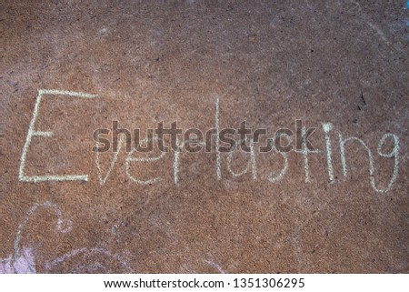the word Everlasting written with sidewalk chalk on gray concrete pavement background