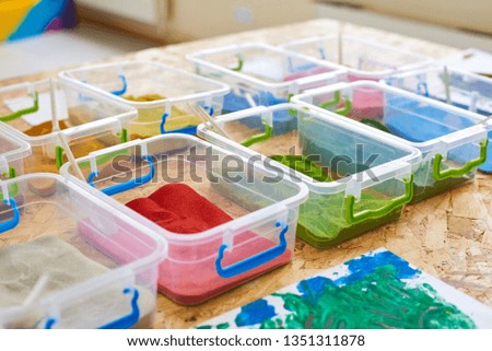 Multi-colored sand for drawing in plastic containers, close-up