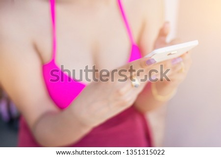 blurred photo,The girl in a colorful bikini is using a smartphone to communicate with her lover through the application.Concept of communication via mobile applications with wireless networks