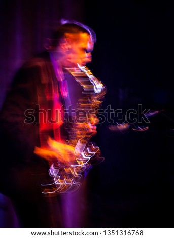 Jazz music concept. Saxophone player performing on stage. Sax player going crazy. Abstract motion blurred image. 