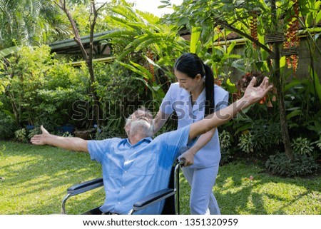 senior man happiness sitting on wheelchair with smiling nurse, takes care and discussion and cheer in the garden at nursing home
