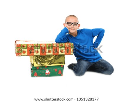 Excited young boy wearing glasses while opening presents against a white background