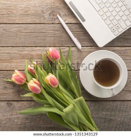  Office table with keyboard, pen, cup of tea and flowers 
