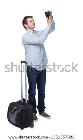 Back view of business man with suitcase with camera. Standing young guy. Rear view people collection. Isolated over white background. Young traveler with a suitcase takes pictures of the sights.