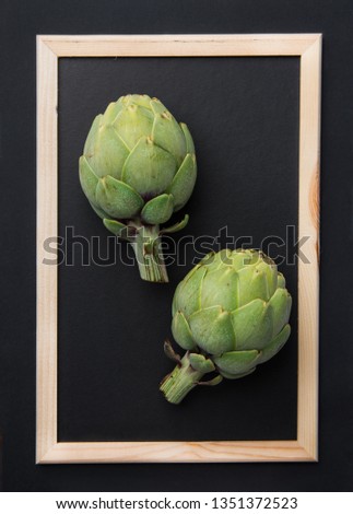Ripe green artichokes on chalkboard in picture frame black background. Creative food poster. Minimalist style. Mediterranean Spanish cuisine healthy plant based diet superfoods concept