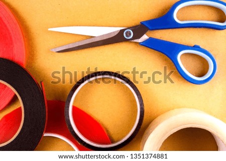 Scissors and adhesive tape lie on the background of a cardboard 