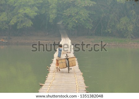 A woman was walking with his bike on the bamboo bridge in Bantul, Yogyakarta 