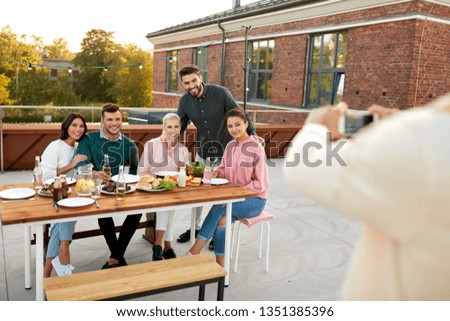 leisure and people concept - happy friends with non alcoholic drinks having barbecue party on rooftop in summer and photographing by smartphone