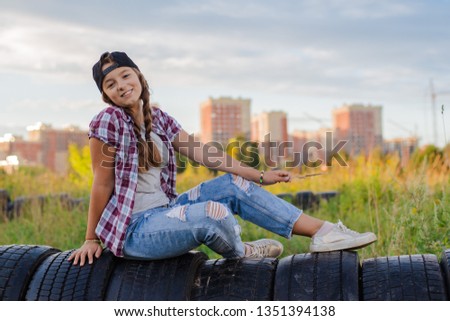 girl teenager in glasses sits the ground city background in the headphones smartphone, sunset. Take pictures of yourself. Loneliness, solitude, trend, misunderstanding, rest, travel, autumn