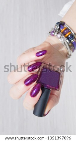 Female hand with long nails and bottle with bordo nail varnish