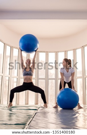 Fitness trainer explaining an exercise with fitness ball to her customer. Pilates