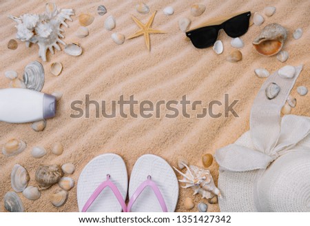 Top view of sandy beach with towel frame and summer accessories. Background with copy space and visible sand texture. left border made of towel