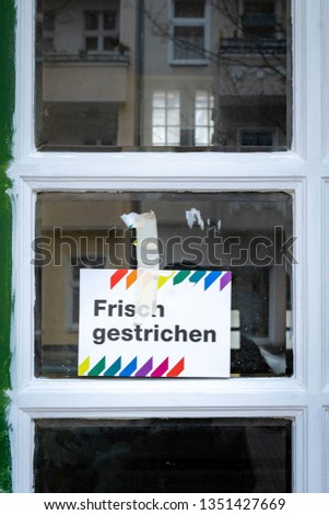 Wet paint warning in German language ("Frisch gestrichen") sign on window