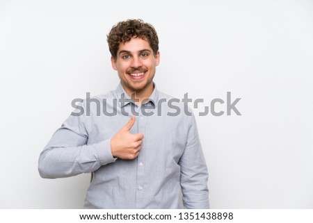 Blonde man over isolated white wall giving a thumbs up gesture