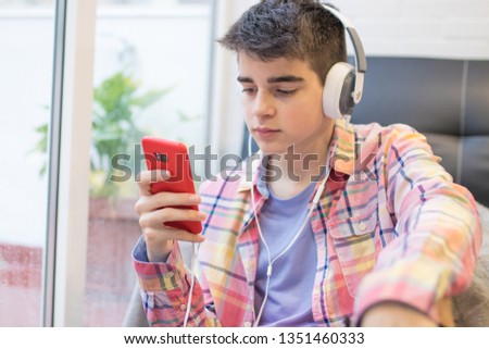 young man listening to music at home with headphones and phone