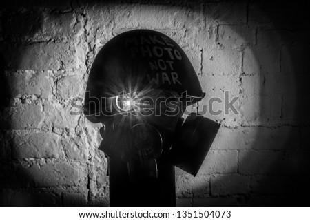 Art picture of military gas mask and green helmet on white brick wall with shadows, the inscription make photo not war on Fatherland defender day. Сoncept of calling world peace without hatred and war