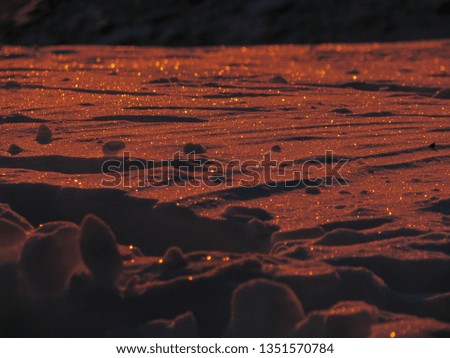 Soft orange red sand-like snow close up that sparkles in the first light of morning 