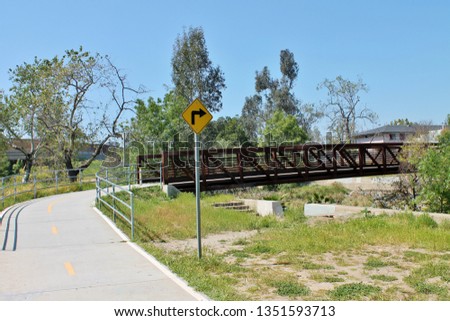 A pedestrian walkway leading to a bridge crossing in a city park
