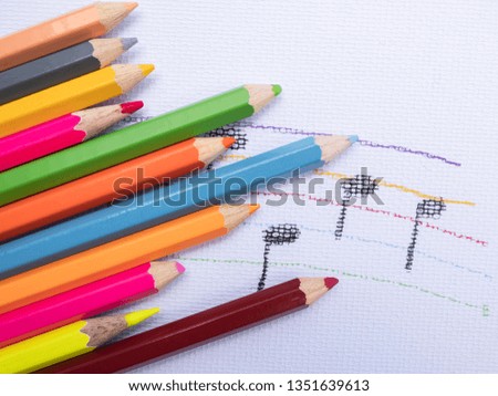 Color pencils place on white paper background with Music note drawing. Education concept.