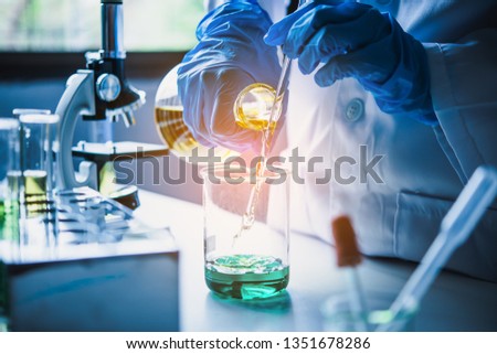  Equipment and science experiments oil pouring scientist with test tube yellow making research in laboratory. Royalty-Free Stock Photo #1351678286