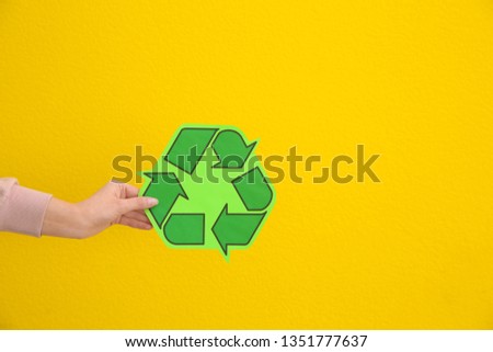 Woman holding recycling symbol on color background, closeup. Space for text