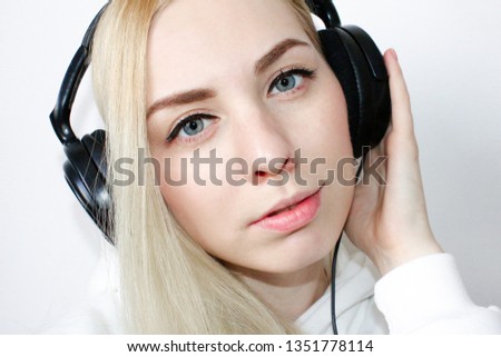 Close-up portrait of happy young woman with blonde hair listening music . Smiling Woman with in headphones listening to music on white background , top view. Attractive funny model in red glasses.