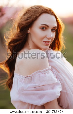 Beautiful young girl under the flowering pink spring tree