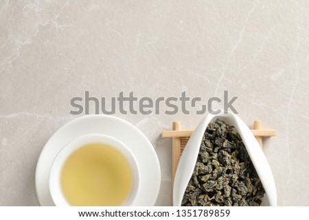 Cup of Tie Guan Yin oolong and chahe with tea leaves on table, top view. Space for text