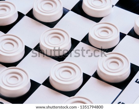 Checkerboard with checkers. Business strategy competition, strategic planning for winning success. Hobby. checkers on the playing field for a game. Black and White Draughts (Checkers). Top view.