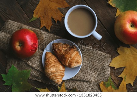 coffee and croissants. apples and autumn leaves on an old wooden table