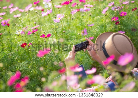 The girl is taking pictures of flowers with a mobile camera.