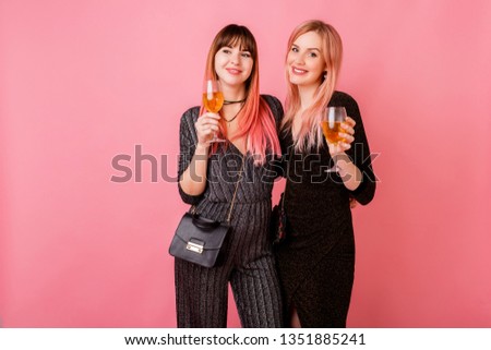 Indoor studio image of celebrating women in party  luxury dress drinking shampagne and have great time together. Pink background.  Bright make up.