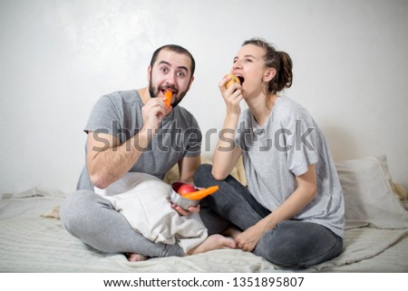 Happy couple eating vegetables at home. White background.
