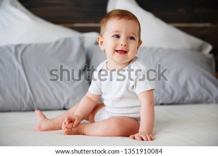 Smiling baby sitting on bed Royalty-Free Stock Photo #1351910084