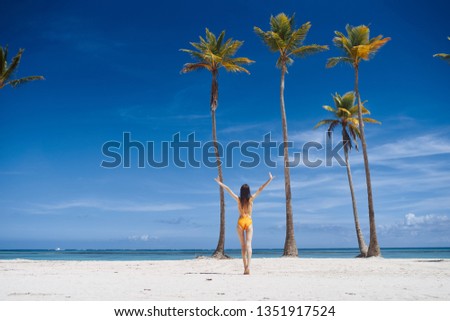 a woman in a full-length swimsuit is standing on an island near tall palm trees                           